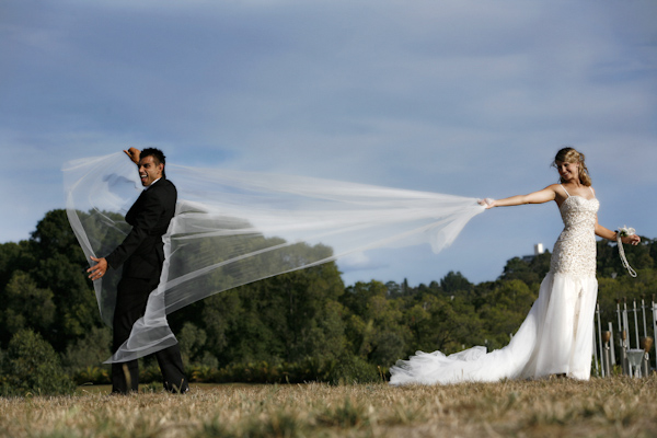 Bride catches groom in her full length veil - wedding photo by Jerry Ghionis